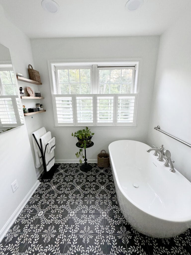 sherwin williams pure white walls and trims, black and white patterned leaf branch tile floor, freestanding white bathrub