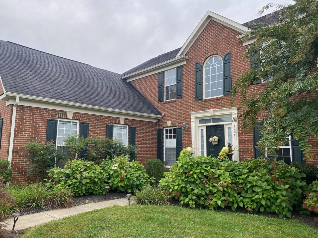 Exterior red brick, with dark almost black shutters and front door.Charcoal dark gray black roof. Cream trim, BEFORE Online paint colour consult with Kylie M Interiors Edesign