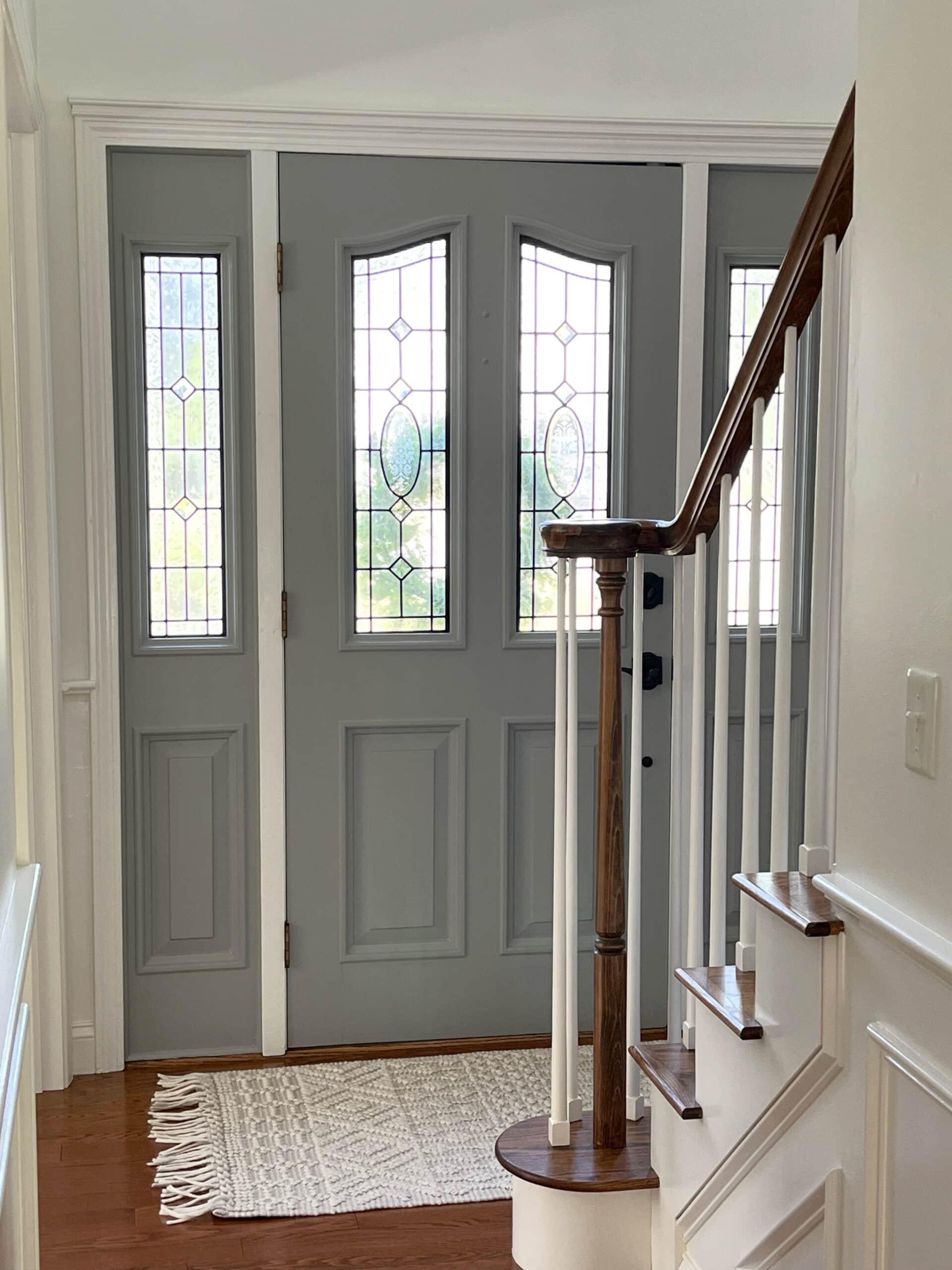 Entrway with oak floor, oak hand railing, Sherwin Williams Gray Matters painted interior or inside of front door, side lights, walls and trims, Benjamin Moore White Dove.