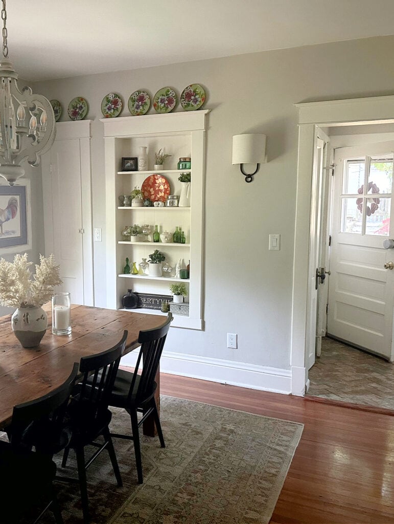 Vintague style home, built-in shelving in wall, wood floor, Sherwin Williams Gossamer Veil, warm gray paint color on walls. Country dining room
