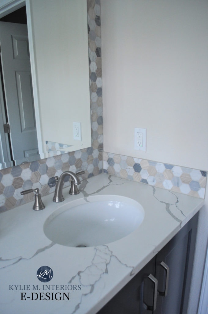 Bathroom with white quartz countertops, dark blue vanity, beige, blue and white hexagon tile and Benjamin Moore Winds Breath paint colour on walls. Kylie M INteriors Edesign, diy update ideas.