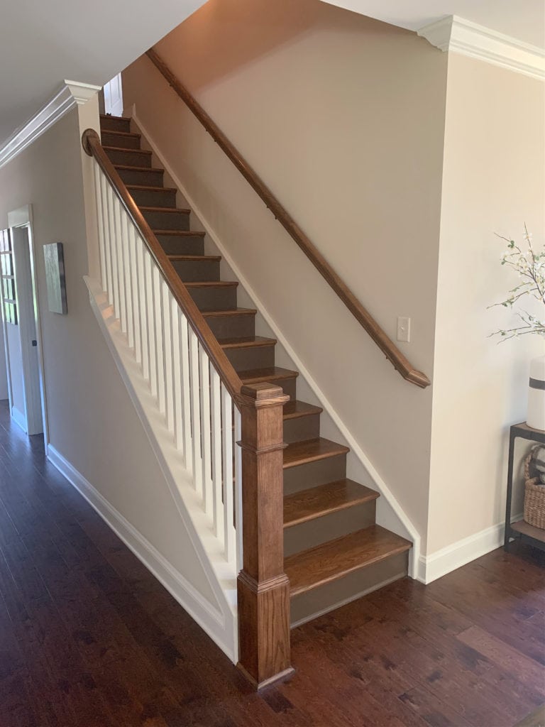 Sherwin Williams Kilim Beige, best warm neutral paint colour on stair wall with red oak cherry toned wood flooring.Update ideas for a 2000s staircase.