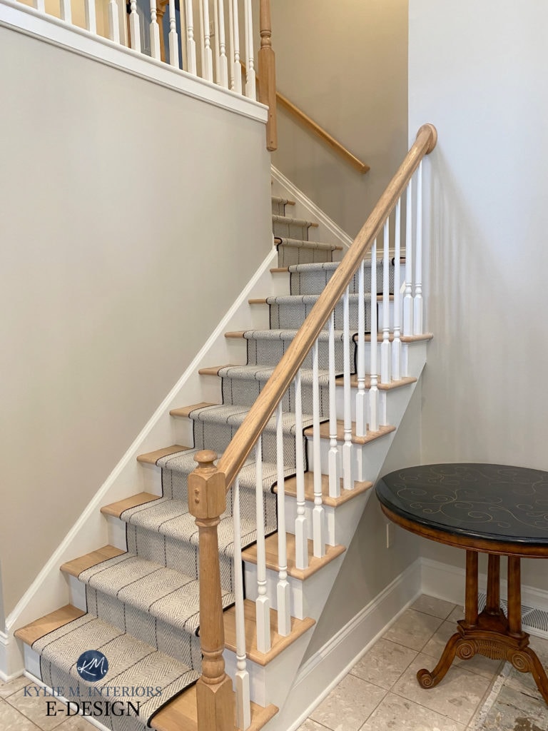 Stairs with striped carpet runner, pebble look tile floor, Edgecomb Gray walls, Benjamin Moore Cloud White trim, natural wood hand rail and white spindles. Update ideas for 2000s staircase, update expert, Kylie M.