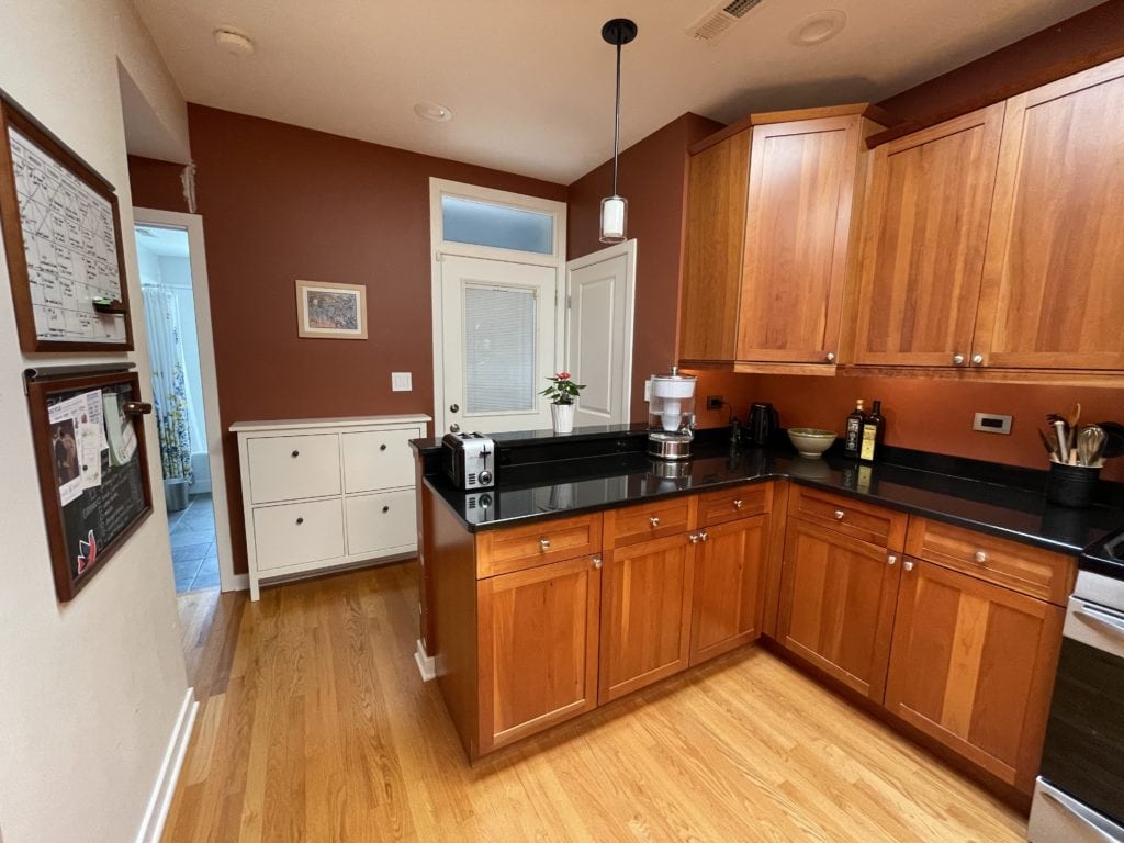 Benjamin Moore California Redwood rust red paint colour, orange wood cabinets, yellow stain wood floor. black granite. Kylie M.