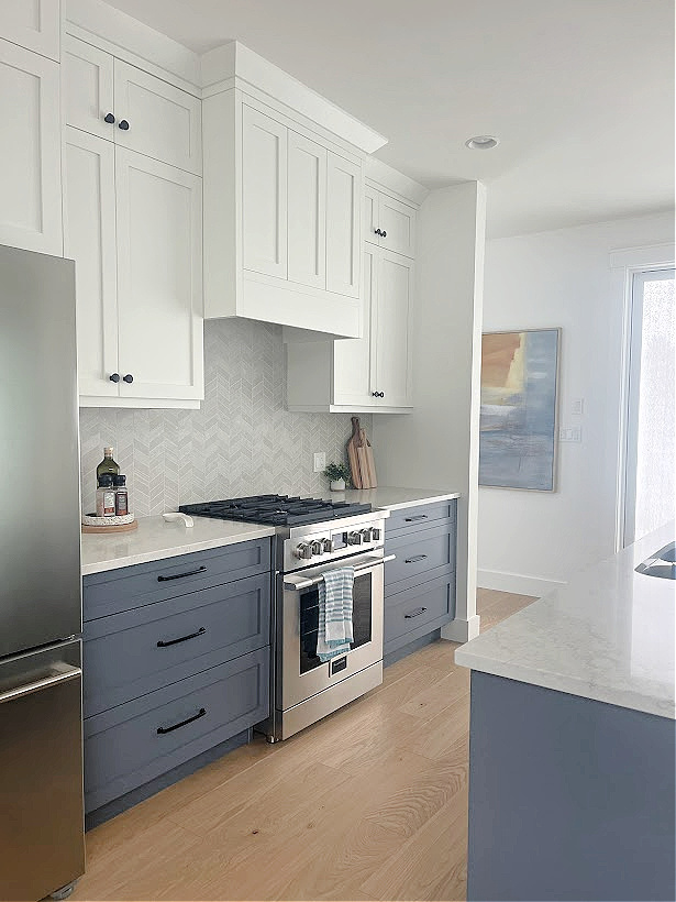 kitchen with fulgor dual fuel gas range, blue lower cabinets, white upper cabinets, white oak flooring