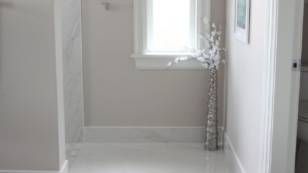 Benjamin Moore Balboa Mist in a bathroom with marble look tile floor and tile baseboards, white trim