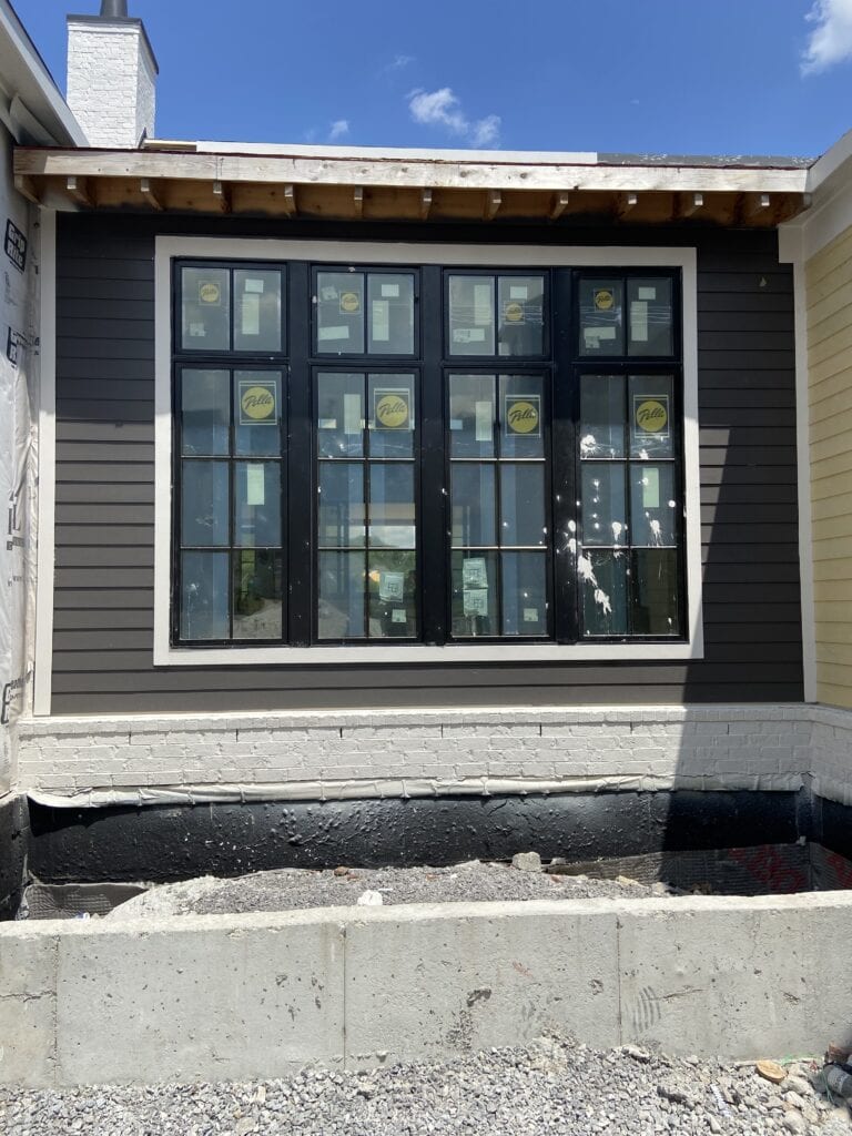 Benjamin Moore Iron Mountain on exterior siding in sun with black windows.