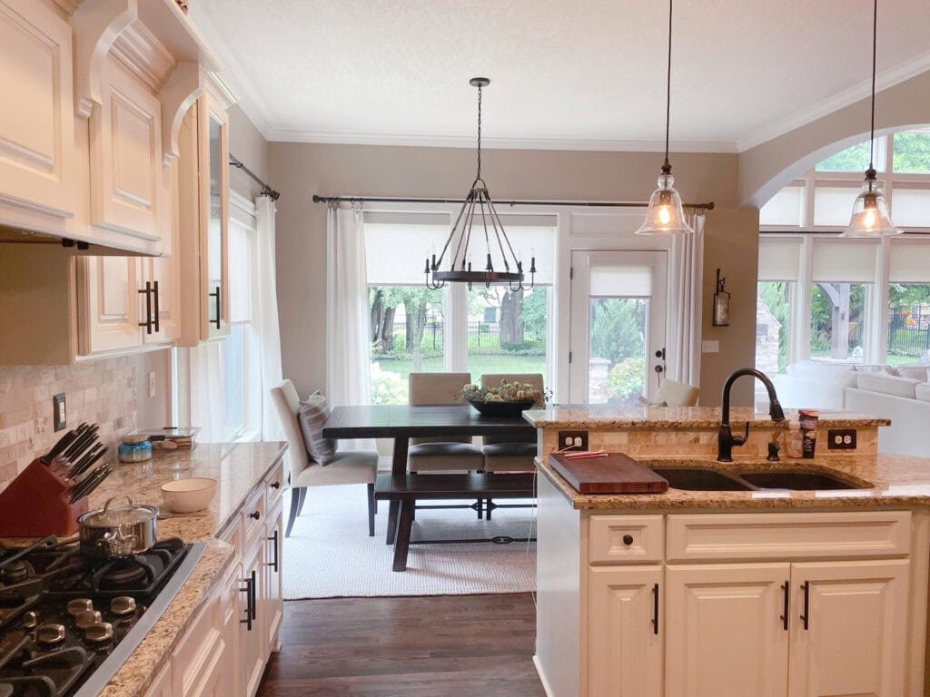 Moderate White painted kitchen cabients with travertine, granite countertop, beige walls.
