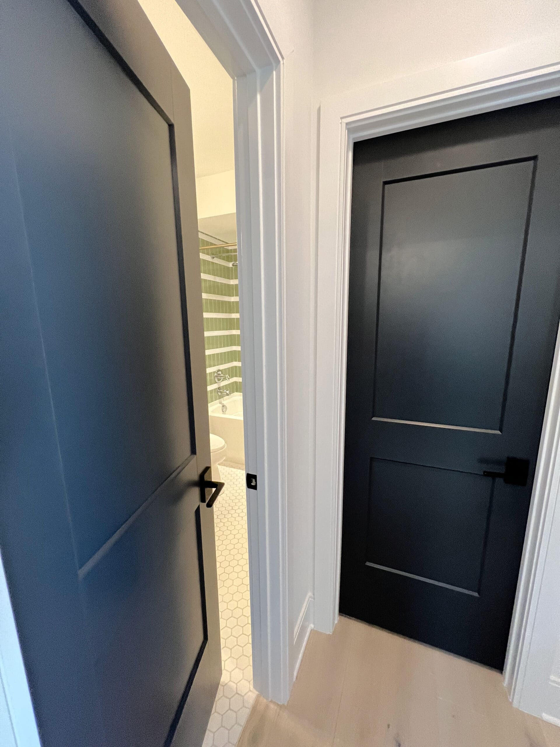 Wrought Iron painted black navy blue interior doors with Eider White walls white trim. Kylie M