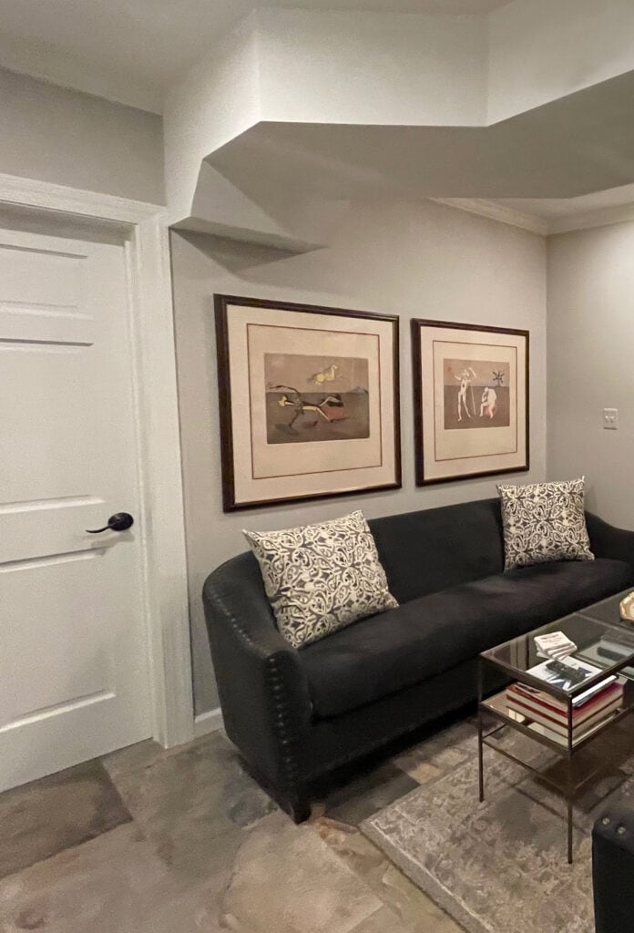 Sherwin Williams Worldly Gray greige paint color in family room dark basement, no windows, Alabaster trim and door, slate tile floor and home decor. Kylie M