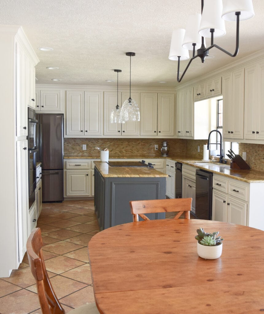 Terra cotta tile colors orange floor, granite countertop, travertine tile, Sherwin Williams Moderate White off white paint color on cabinets, dark black stainless appliances.