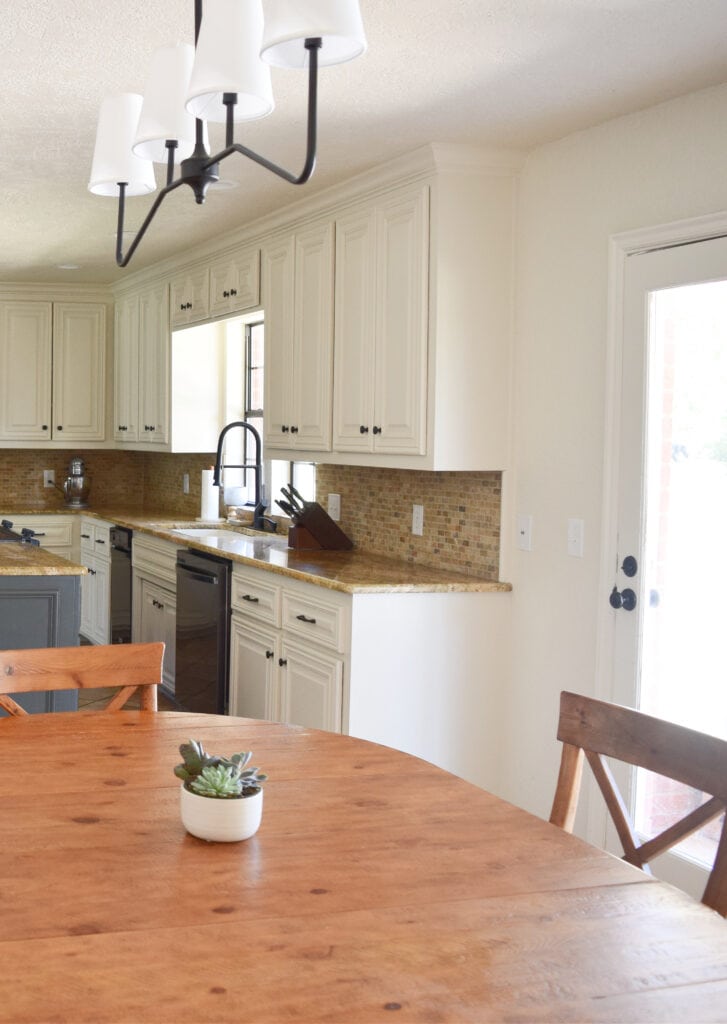 off-white beige cabinets, Sherwin Williams Moderate White, granite countertop, travertine tile backsplash, beige walls. Kylie M Edesign, online color consultant