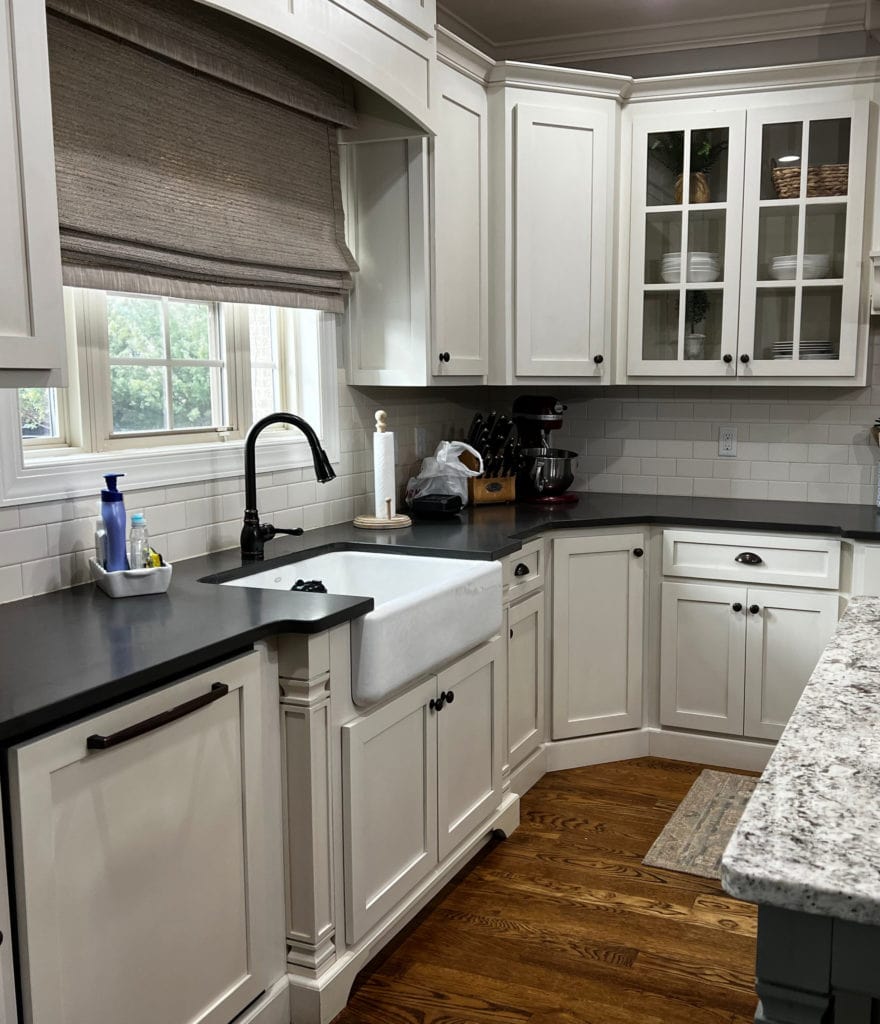 Benjamin Moore Linen White cream painted kitchen cabinets, black granite countertop, oak wood flooring, white farmhouse sink, subway tile backsplash