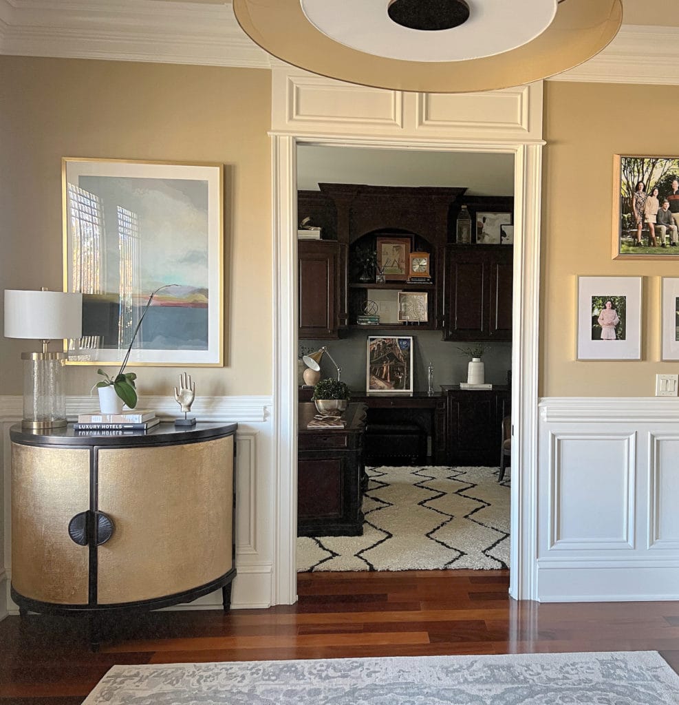 Paint color similar to Sherwin Williams Harmonic Tan. Trim and wainscoting Creamy. Foyer with home decor and red toned flooring