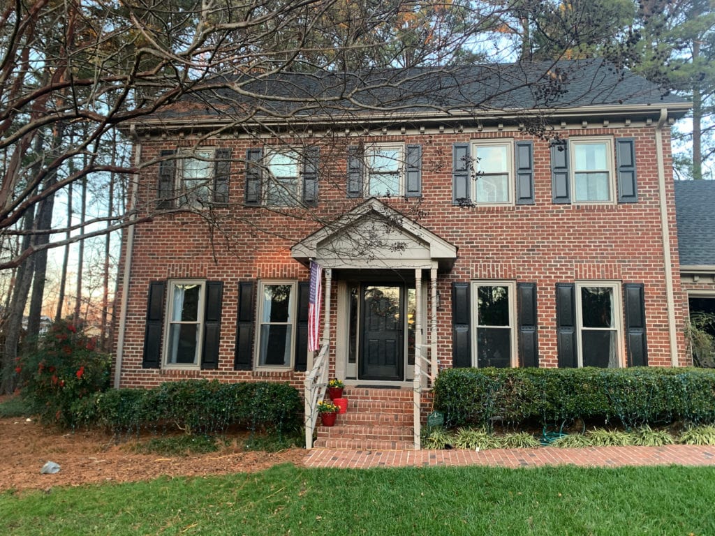 Red brick traditional, period-style exterior, black shutters and Black front door, red orange brick, Keystone Gray greige trim colour, dark charcoal roof