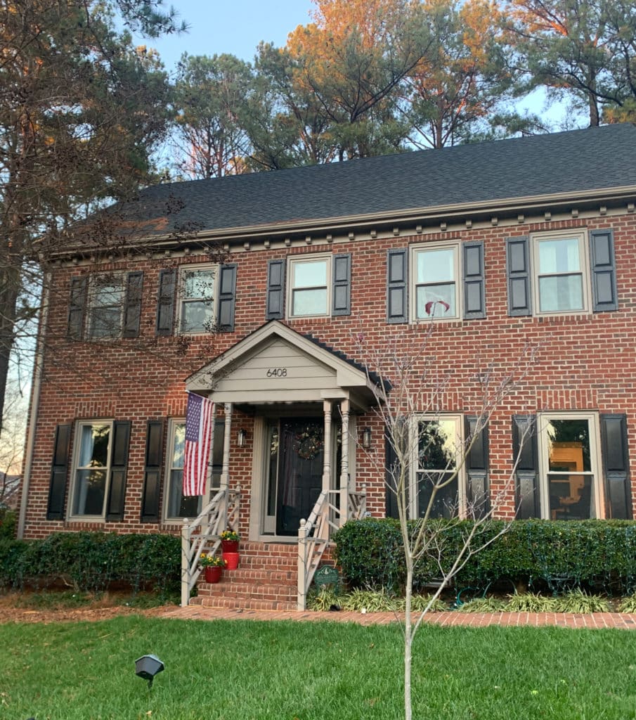 Red-orange brick exterior, traditional or colonial style, Sherwin Williams Keystone Gray trim, best greige, black front door and shutters.
