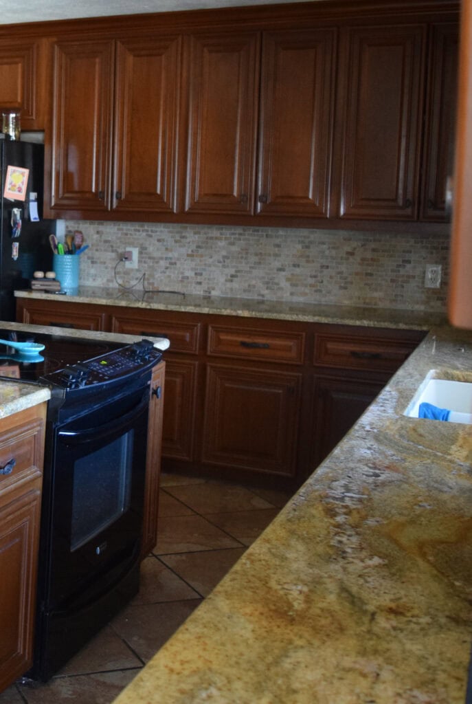 BEFORE kitchen cabinets, wood, granite countertop, travertine tile backsplash.