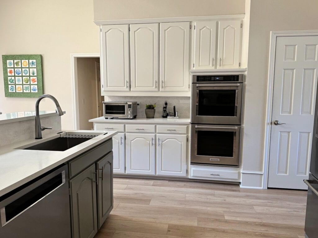 Kitchen painted maple cabinets and trim, Benjamin Moore White Dove, walls Maritime White soft beige. Stainless steel, green Antique Pewter lower cabinets, white quartz