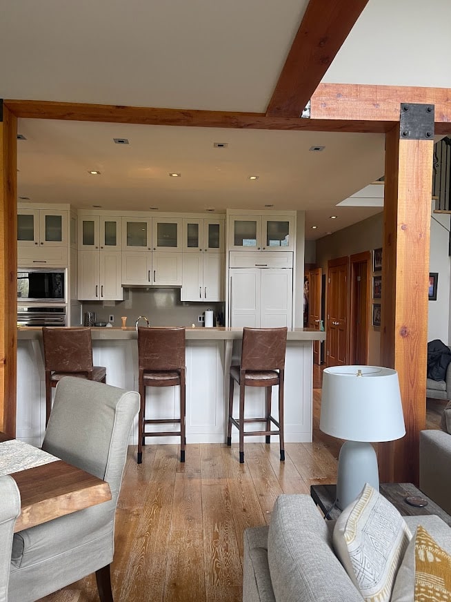 Benjamin Moore Natural Cream painted kitchen cabinets, greige taupe quartz countertop, raised island, wood beams, wood trim.
