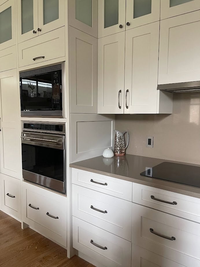 Kitchen cabinets painted Benjamin Moore Natural Cream, brown quartz countertops, oak floor.