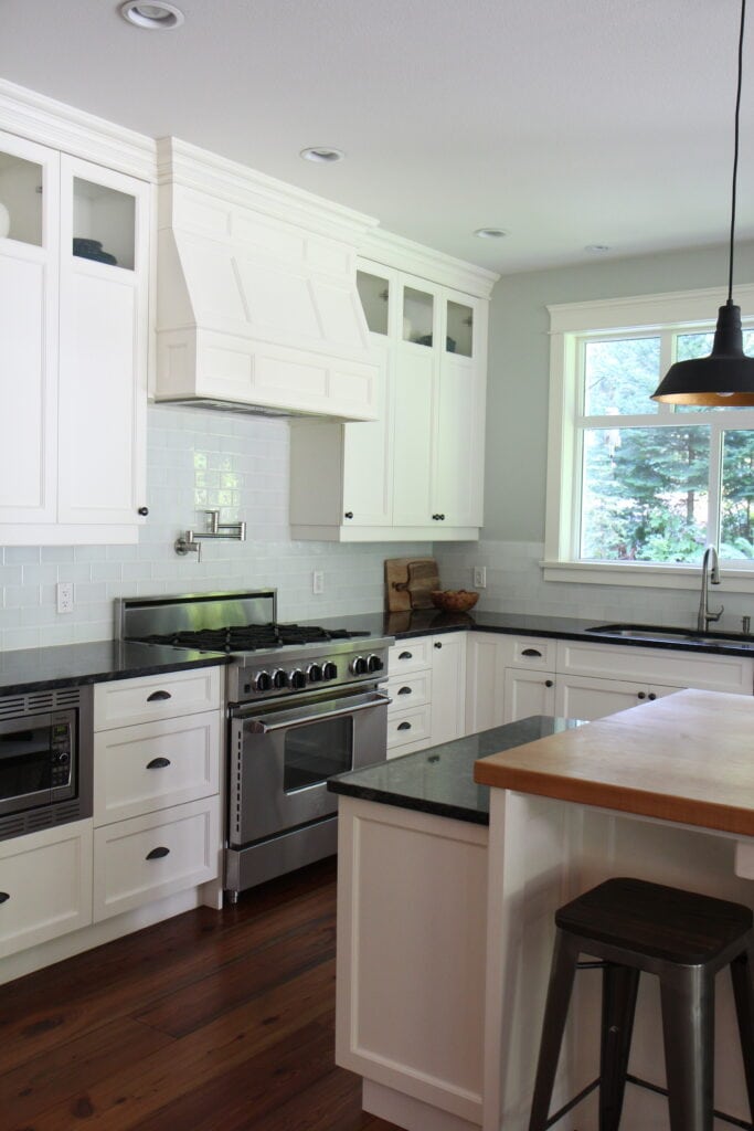 Black granite countertop, butcher block island, wood floor, Cloud White cabinets, Benjamin Moore Gray Cashmere paint color on walls