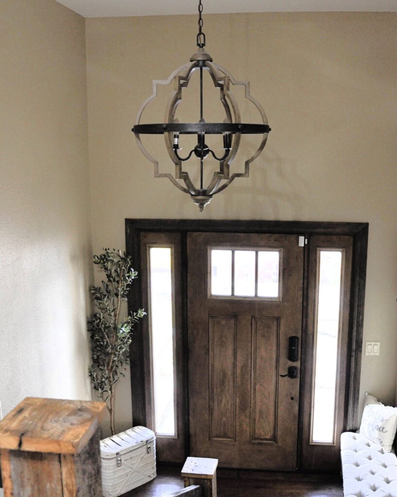 Sherwin Williams Basket Beige in split level foyer with rustic wood door and dark wood trim, pendant light.