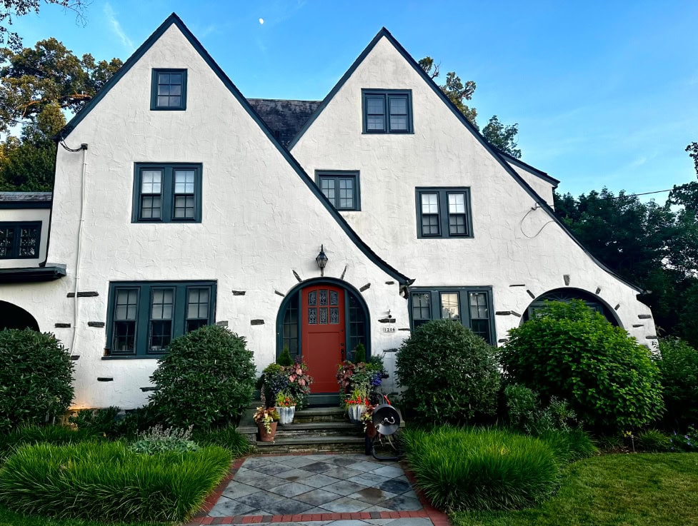 Tudor style stucco exterior painted Sherwin Williams warm white, dark teal trim, Still Water, Rustic Red front door, exterior color palette. Kylie M Interiors