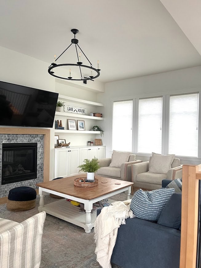 Livingroom with white built ins, Benjamin Moore White Dove, tv above fireplace, marble around stone fireplace, white oak surround, blue sofa and accents, square coffee table.