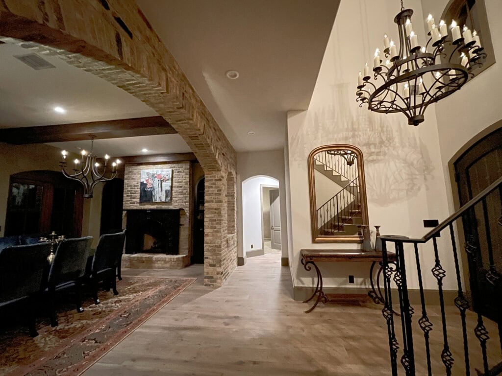 Beige brick on interior walls, Aesthetic White off white beige walls, wrought iron chandelier and stair railing, Spanish or Tuscan style. Kylie M oNline paint color expert