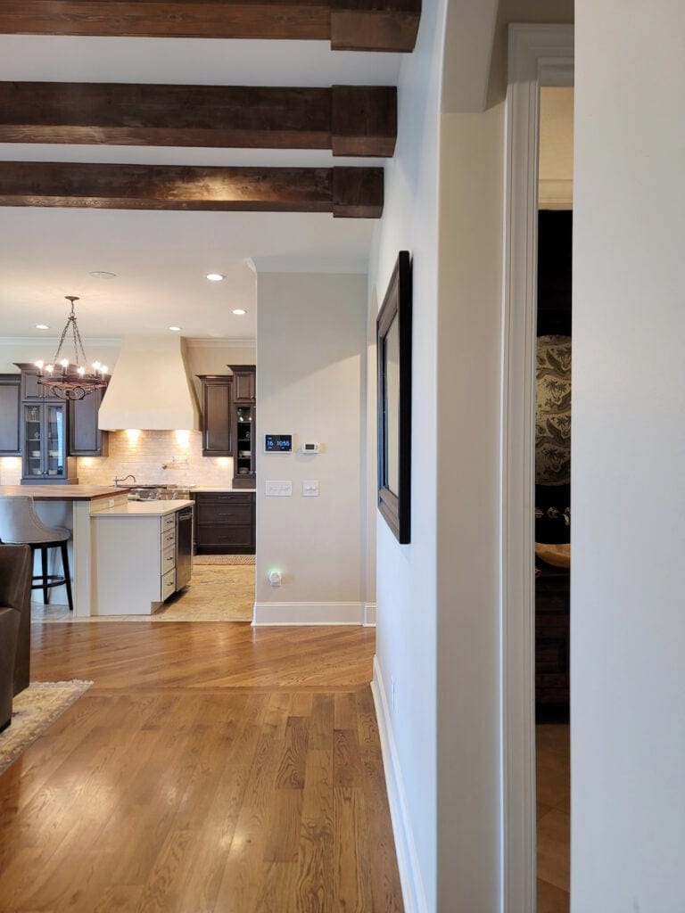 Benjamin MOore Winds Breath match with wood floor, cream cabinets on island, dark wood upper cabinets, wood beams.