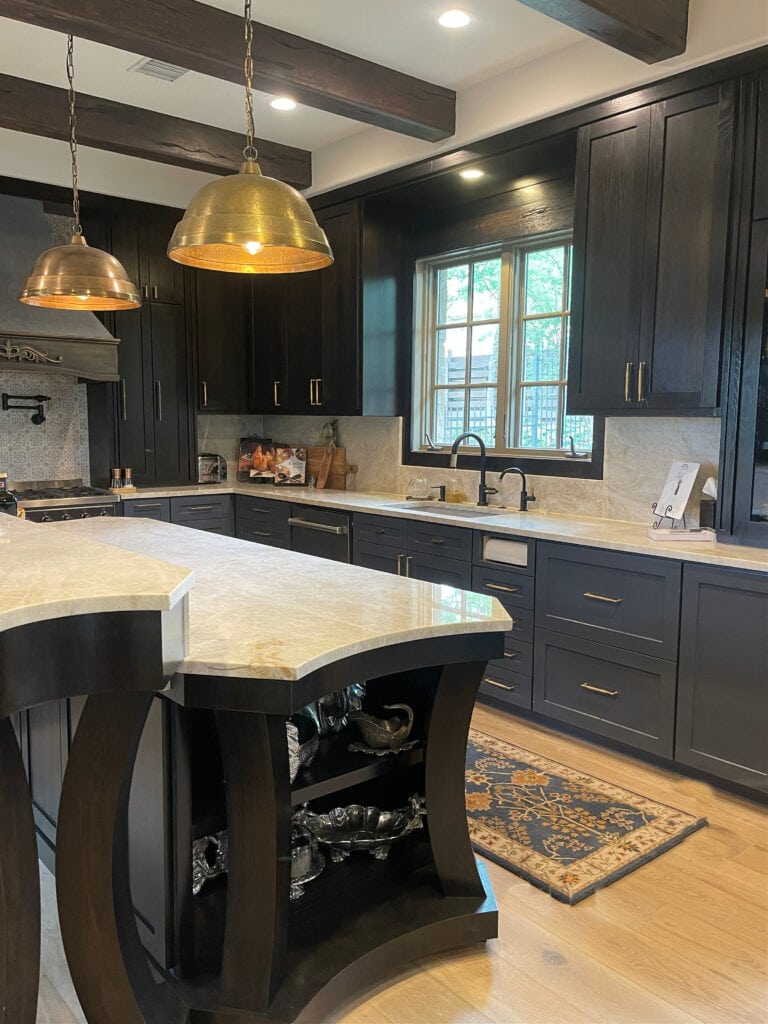 Benjamin Moore Mysterious, dark blue black painted lower cabinets, island upper cabinets stained dark wood, granite quartzite look countertops, beams, okay floor kitchen. Kylie M Edesign