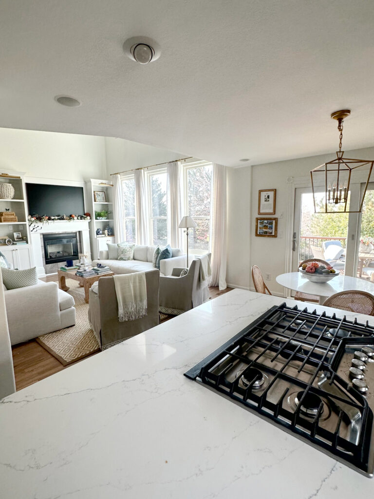 Sherwin Williams Greek Villa warm white paint color on walls, Chantilly Lace trim, white quartz countertop, open concept kitchen living room. Kylie m