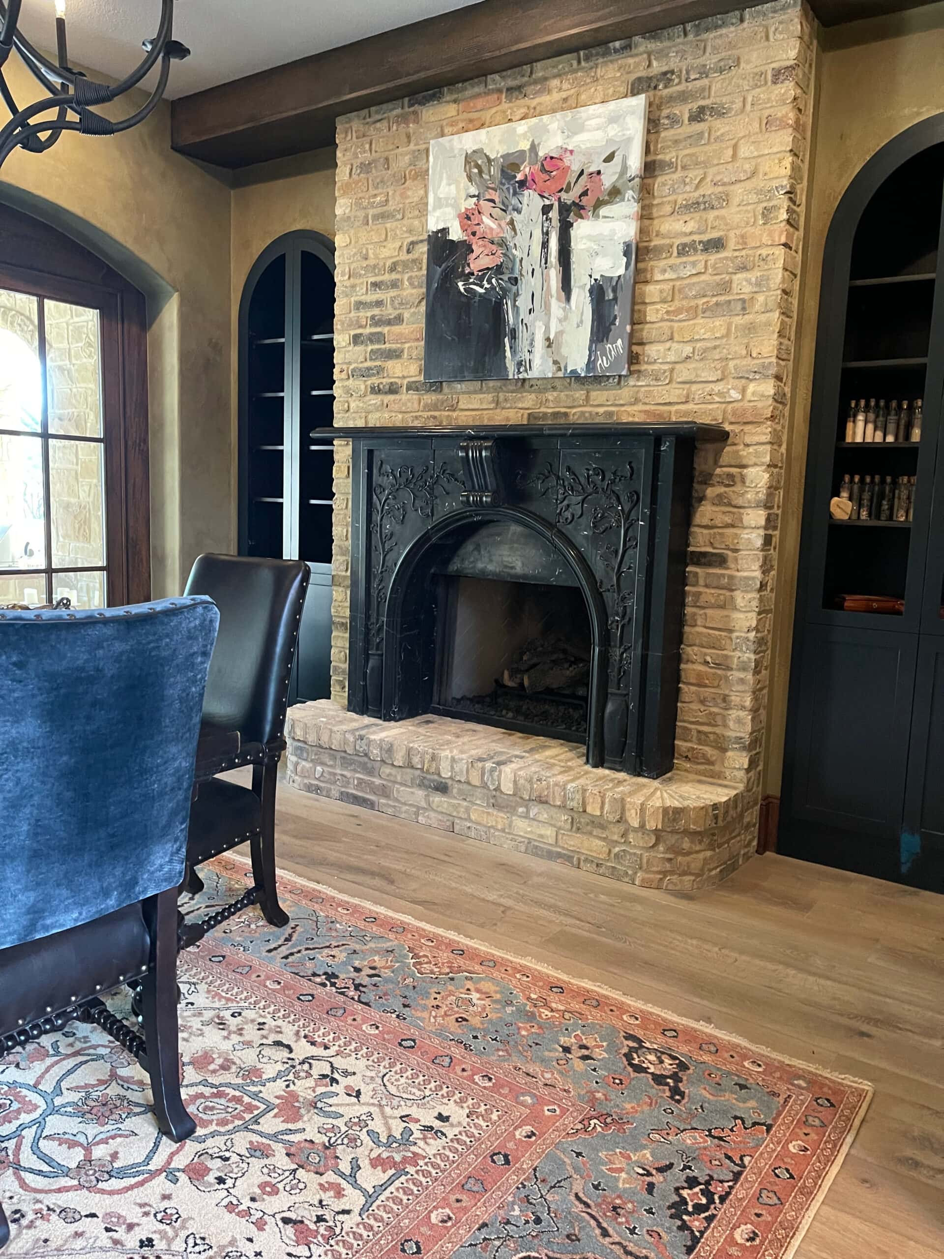 Tuscan style home, dining room, brick fireplace, black marble fireplace surround and mantel, dark wood beam, arched door. Kylie M INteriors Edesign, glazed walls