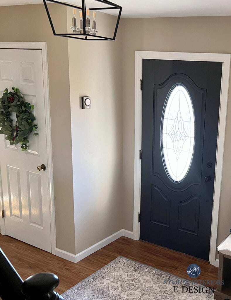 Benjamin Moore Bar Harbor Beige, orange-pink beige with white trim, black painted inside front door. wood floor entryway.