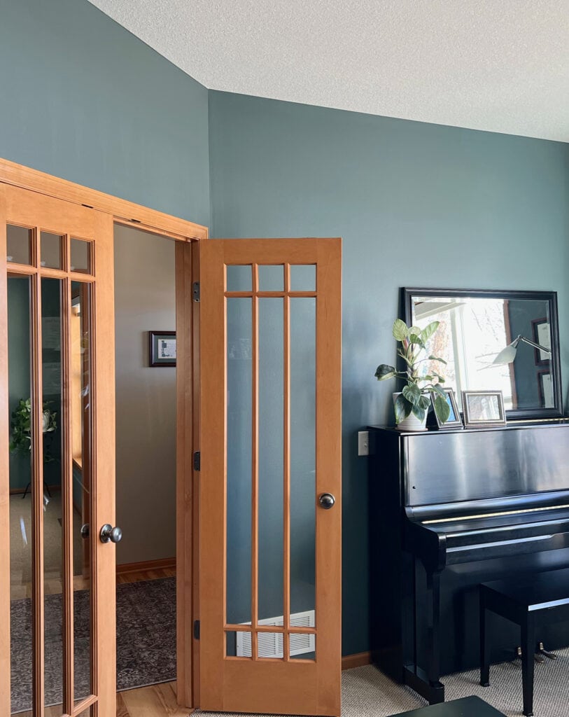Benjamin Moore Knoxville Gray, wood french doors with orange stain, wood trim, beige carpet, black piano. Best blue green paint colors. Kylie M