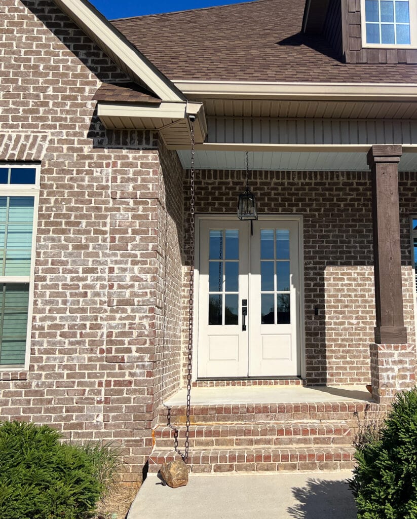 Front door in sun, Benjamin Moore Edgecomb Gray with red brown burguny roof and brick exterior with almond windows