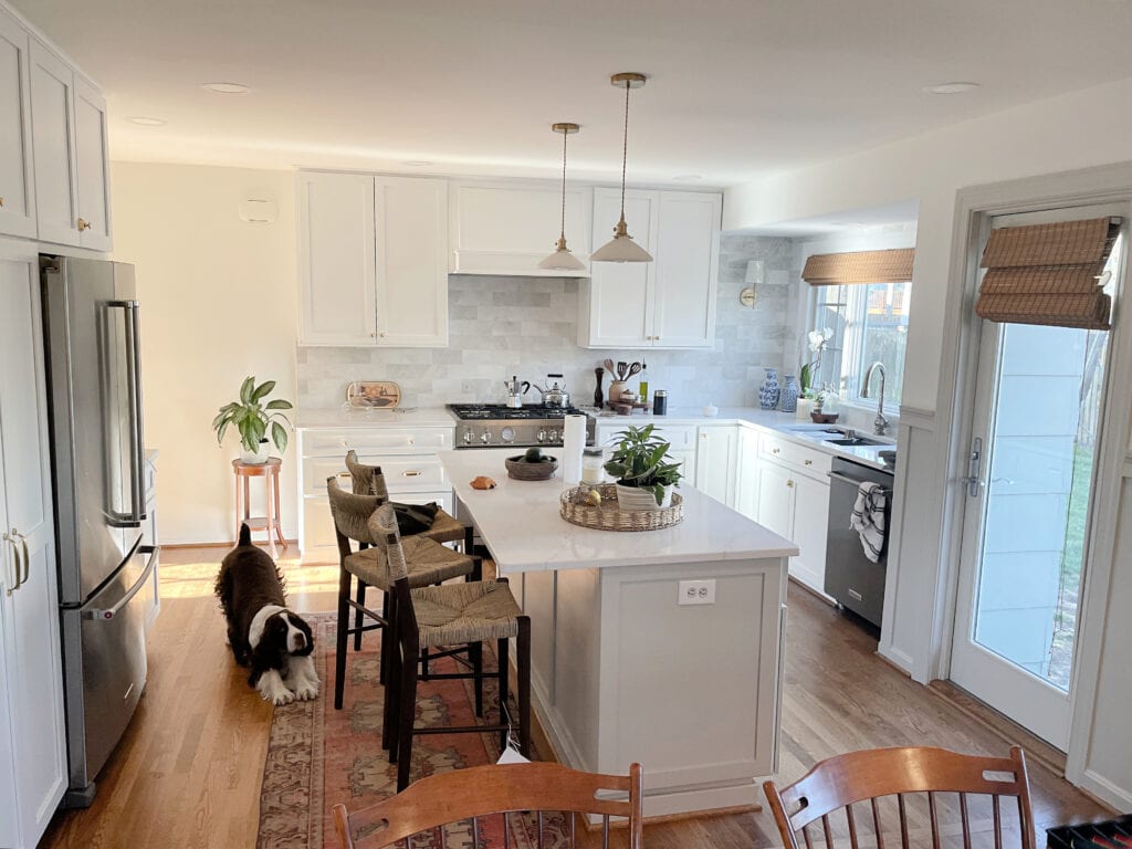 Kitchen remodel, Benjamin Moore Chantilly Lace painted white cabinets, Sherwin Williams Agreeable Gray painted island, warm gray greige trim and board and batten. Wood flooor. Marble backsplash. Kylie M online paint color expert with Truley Home