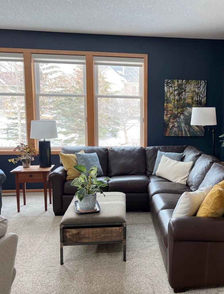 Orange stain wood trim in family room or living room, beige carpet, LEATHER sectional, Benjamin Moore Hale Navy accent wall. Kylie M INteriors