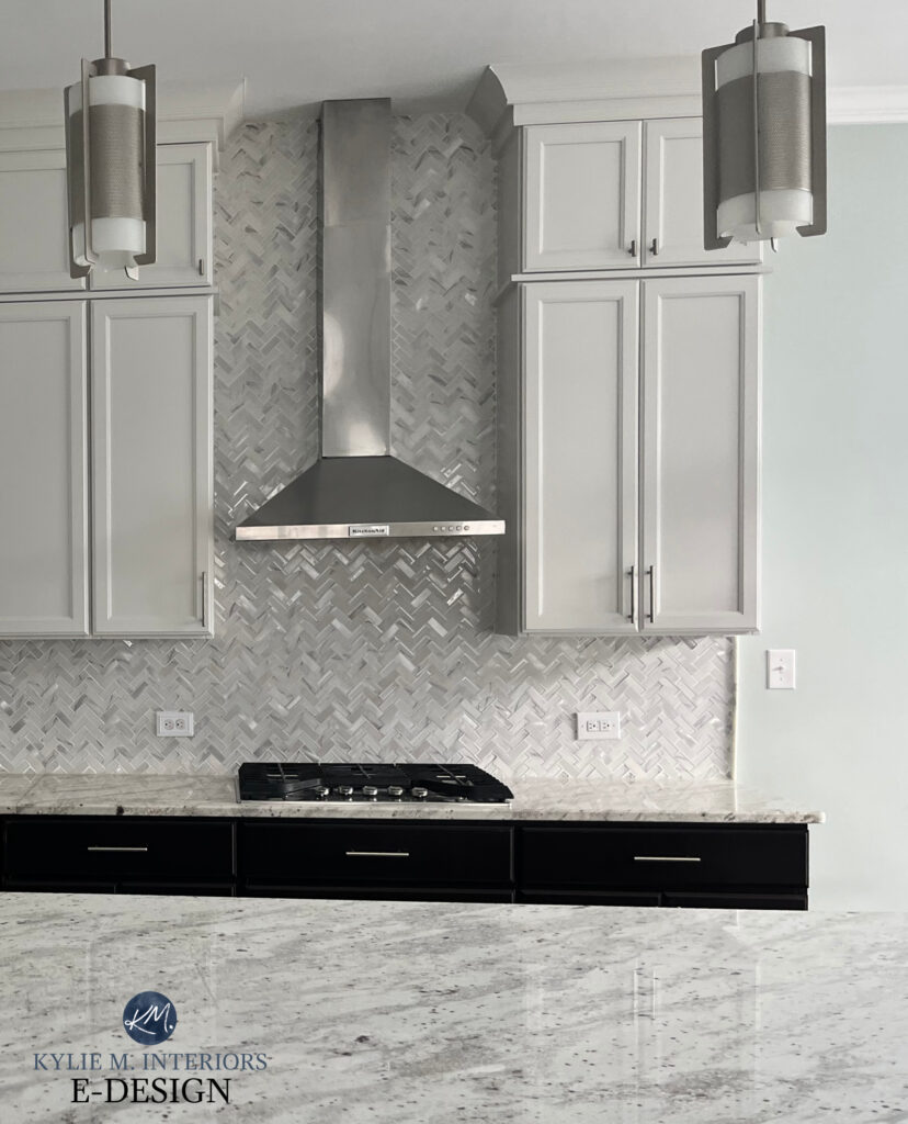 Painted warm gray light greige cabinets, Sherwin Williams Drift of Mist, marble glass chevron herringbone backsplash tile, granite countertop