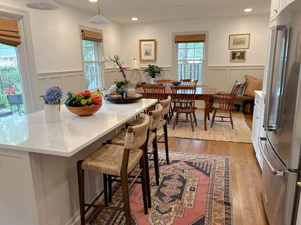 Sherwin Williams Agreeable Gray warm gray or greige painted kitchen island, trim and board and batten on lower walls. Kylie M Interiors paint color expert,Dining area wood furniture, Benjamin Moore Chantilly Lace walls,