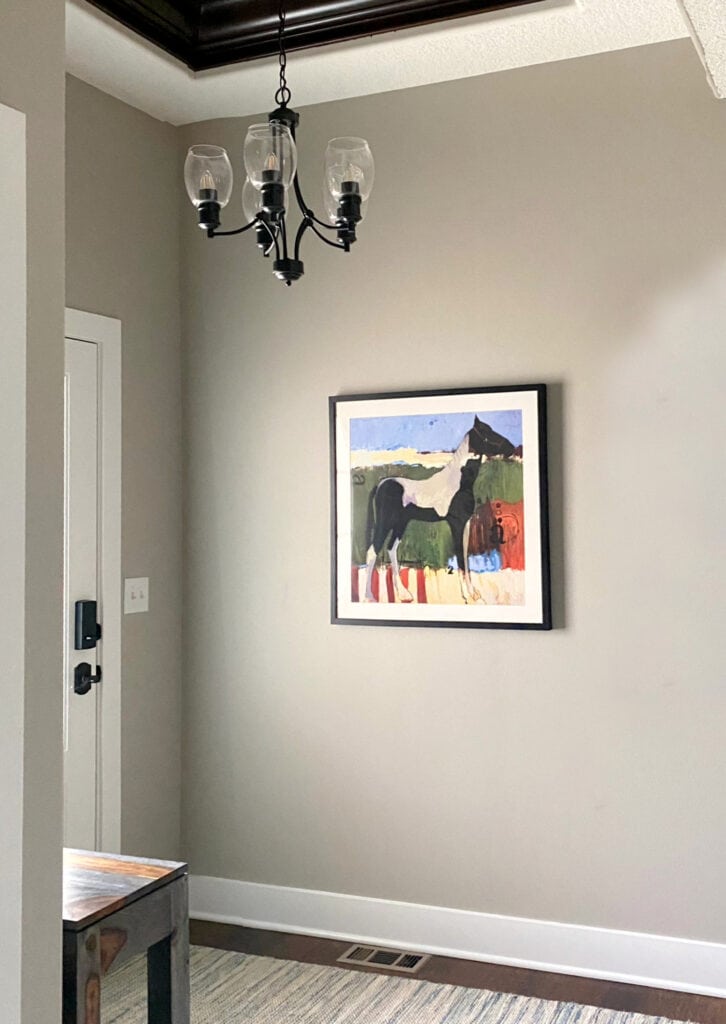 Sherwin Williams Anew Gray in entryway with wood floor, chandelier. Warm greige taupe paint color.