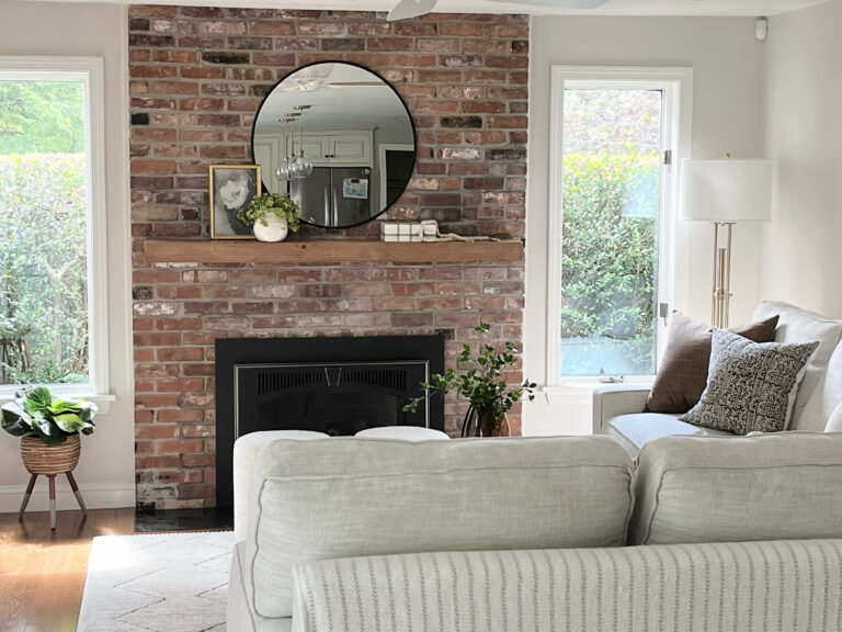 Sherwin Williams Egret White, Family room, brick fireplace in red, orange, pink. Wood mantel with mirror and home decor. Fabric sofa. Kylie M Interiors online paint color expert