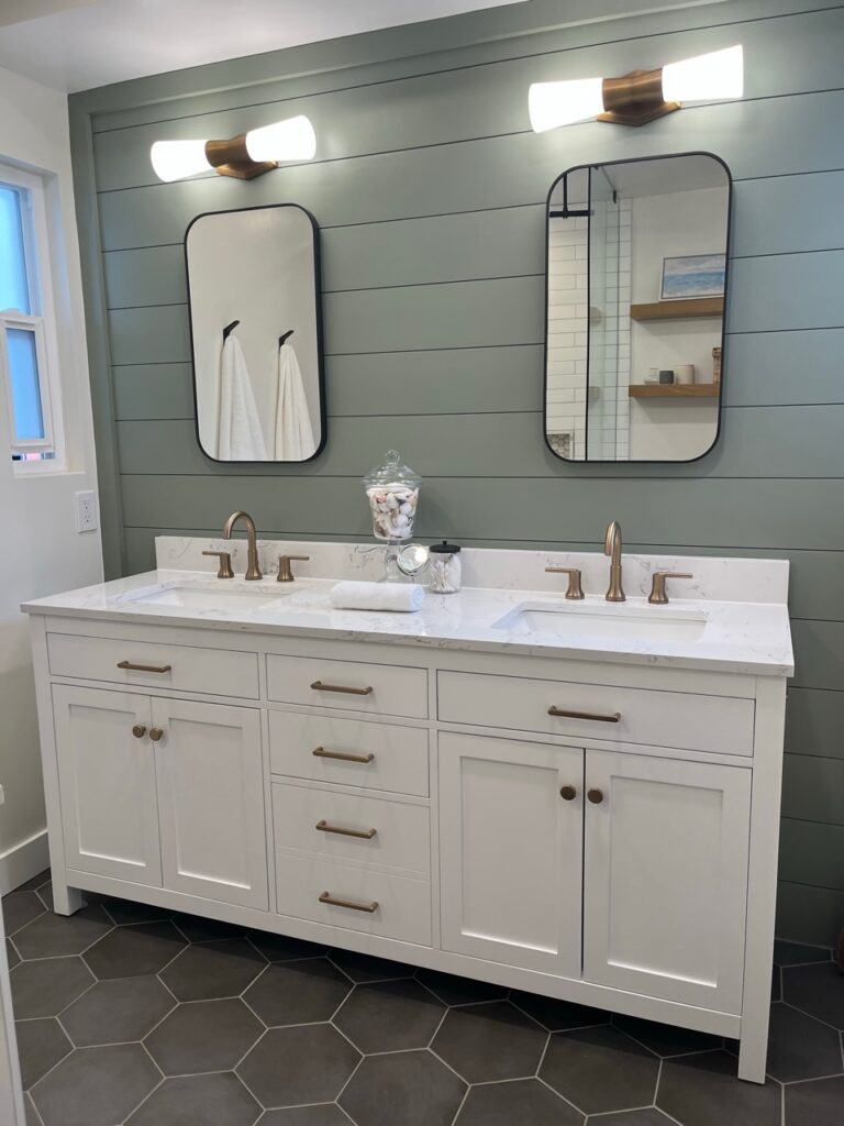 Sherwin Williams Evergreen Fog shiplap accent wall behind vanity, gold brass hardware, Alabaster walls, dark gray black hexagon tile floor, white vanity. Marble look quartz counte