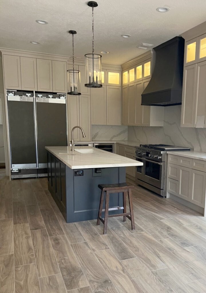 Sherwin Williams Sandbar beige tan painted cabinets, MSI Calacatta Idillio white quartz countertop, soft black Iron Ore painted island, range hood, quartz backsplash.
