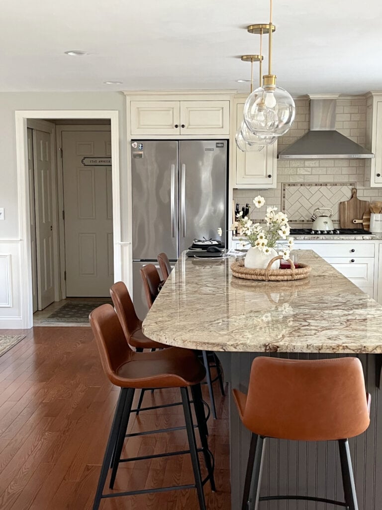 Sherwin Williams dark greige painted island, Urbane Bronze, cream and glazed kitchen cabinets, subway tile, leather barstools, red stain oak floor, greige walls,
