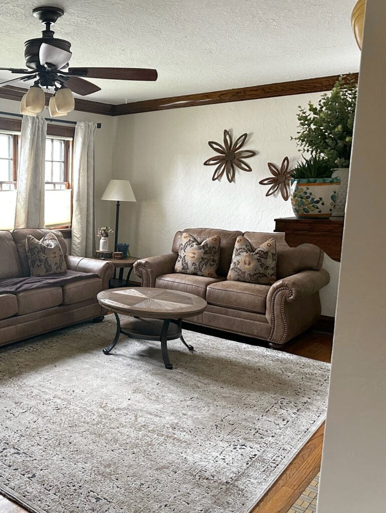 Dark wood trim in old home, wood floor, Benjamin Moore Maritime White paint color on walls, brown microfibre sofa