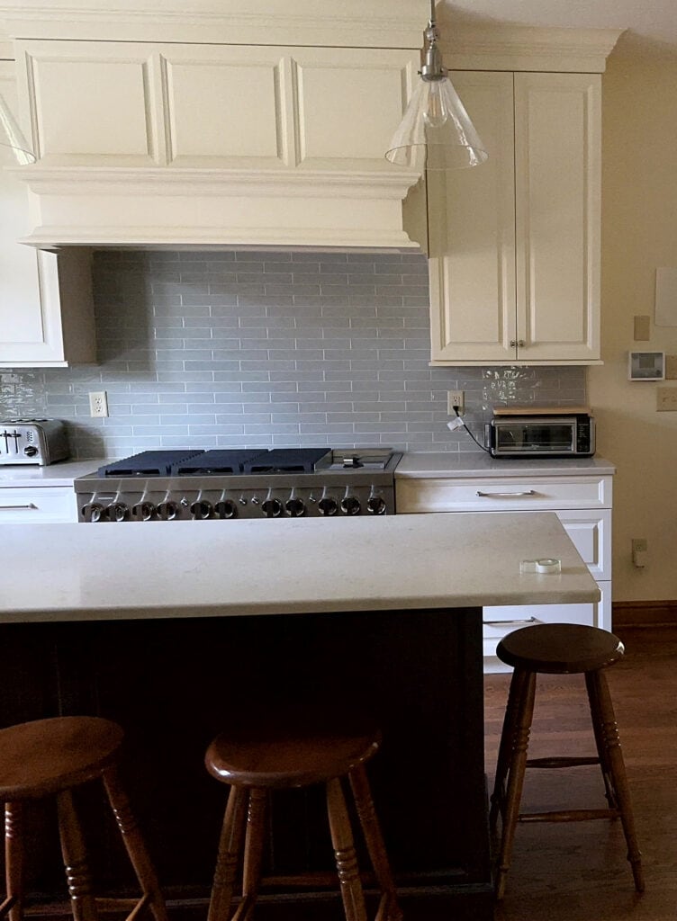 Pearl White custom cream off-white kitchen cabinets, similar to Navajo White with too cold gray backsplash tile.