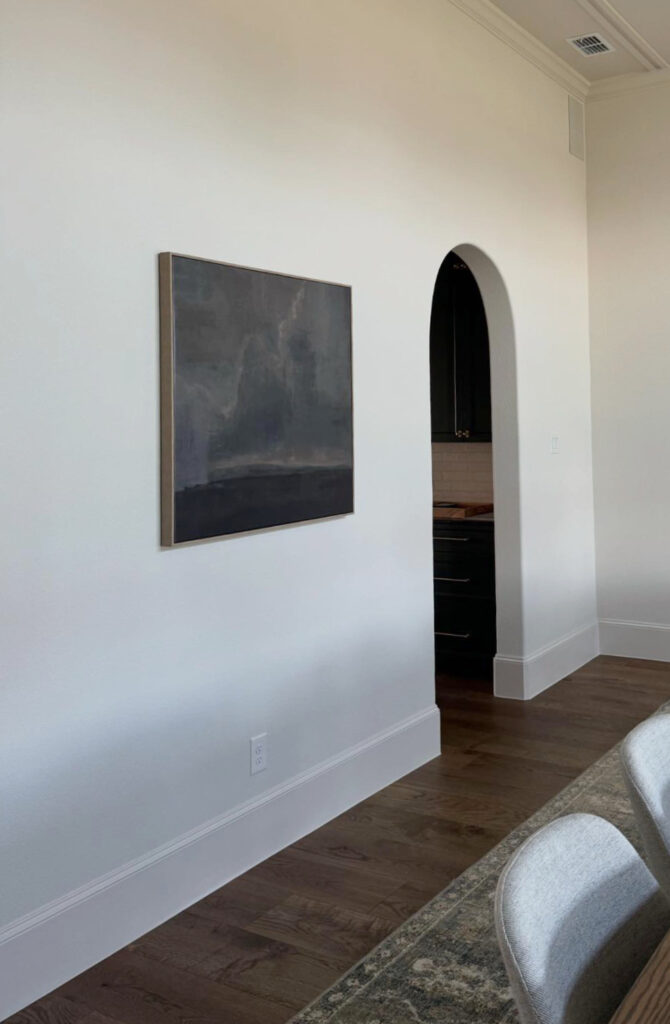 Sherwin Williams Aesthetic White off white beige on walls and trim, arched doorway, wood floor.