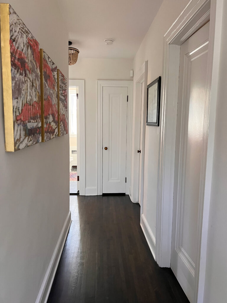 Sherwin Williams Alabaster and Extra white paint color on trims and walls, dark wood floor, hallway with doors. Kylie M Online Paint consulting client photo