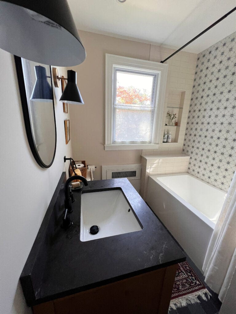 Sherwin Williams Neutral Ground, light warm neutral paint color walls. Small bathroom, black countertop on vanity, Kylie M Online Consulting, client photo
